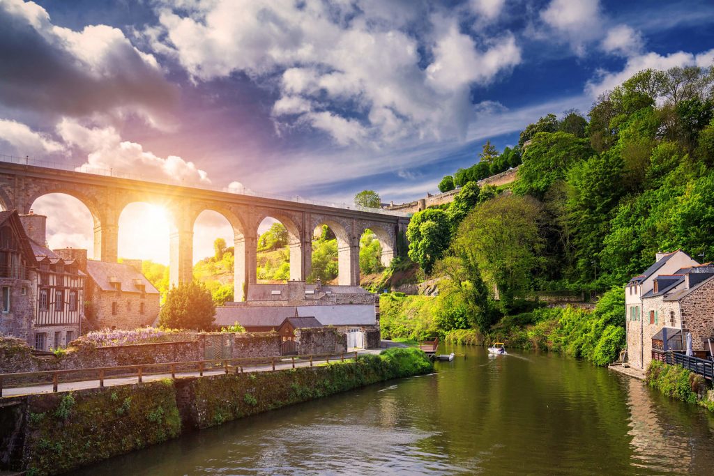 Dinan medieval town viewed from the River Rance, with the historic stone viaduct bridge rising above the riverside port, Brittany, France